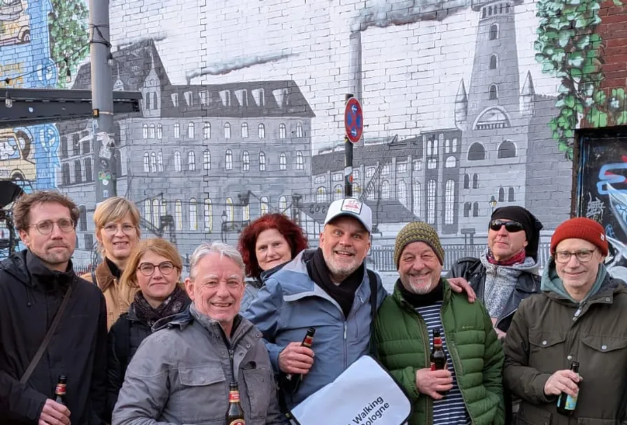 Gruppe von Menschen lächelt vor Wandgemälde.