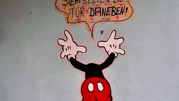 Cartoon character with speech bubble on wall.