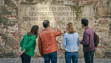 Vier Personen lesen historische Wandinschrift.
