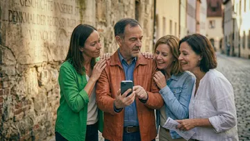 Group of adults looking at a smartphone outdoors.