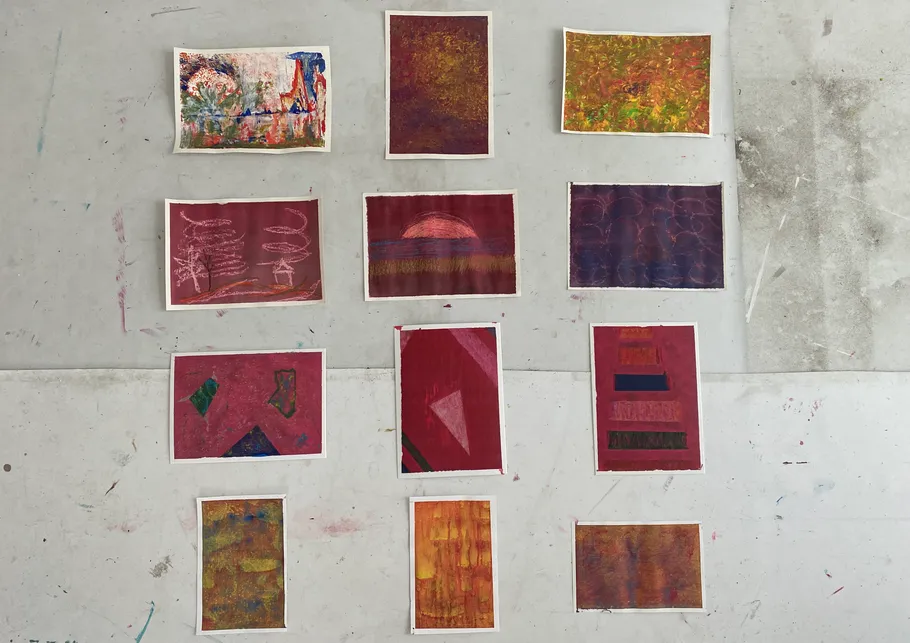 Twelve abstract art pieces arranged on the floor.