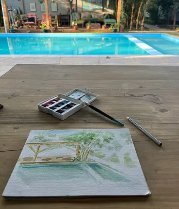 Watercolor painting setup by a swimming pool.