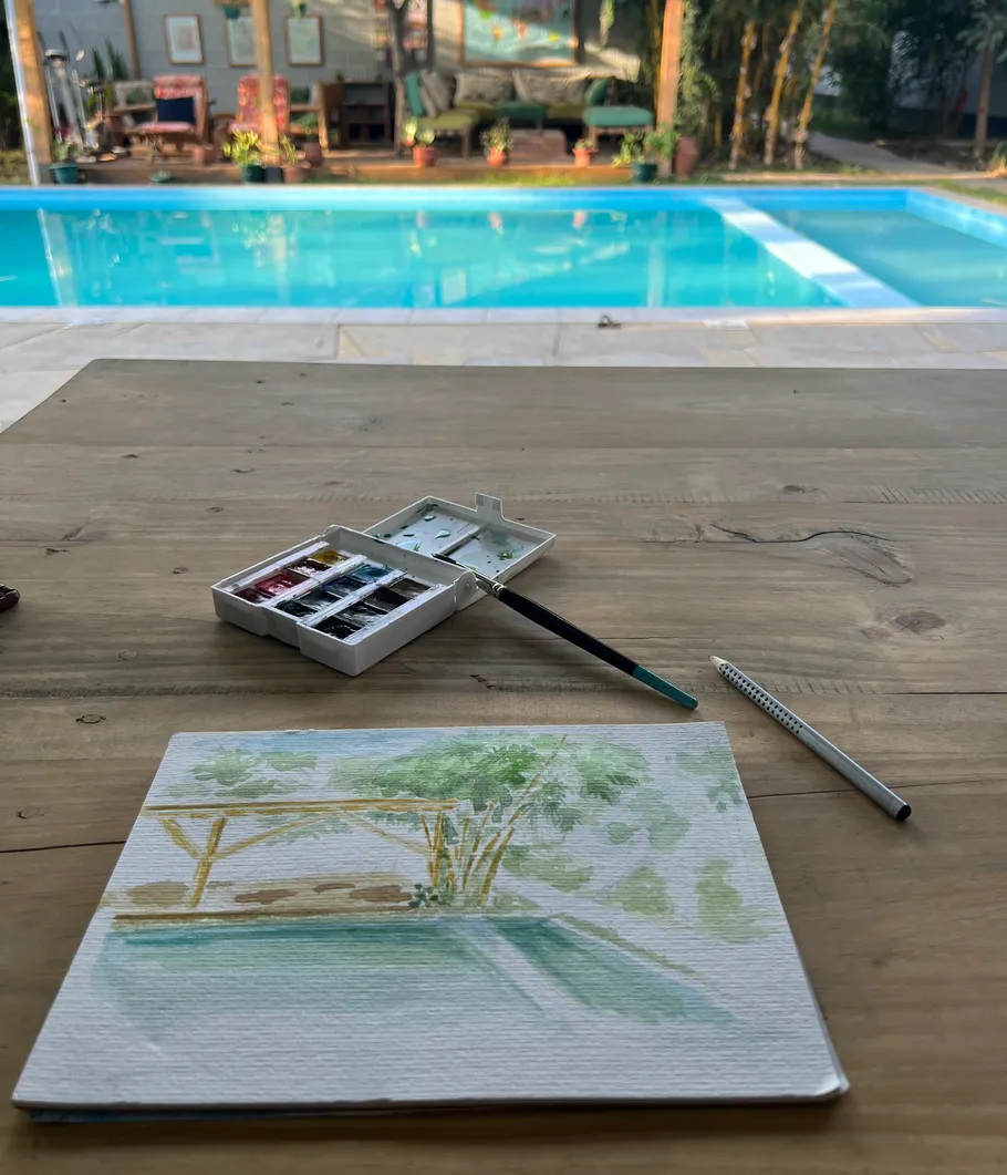 Watercolor painting setup by a swimming pool.