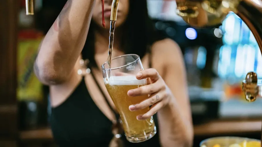 Person gießt Bier aus Zapfhahn ins Glas.