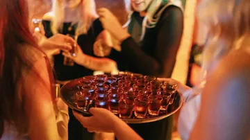 Personen halten Getränketablett auf einer Party.