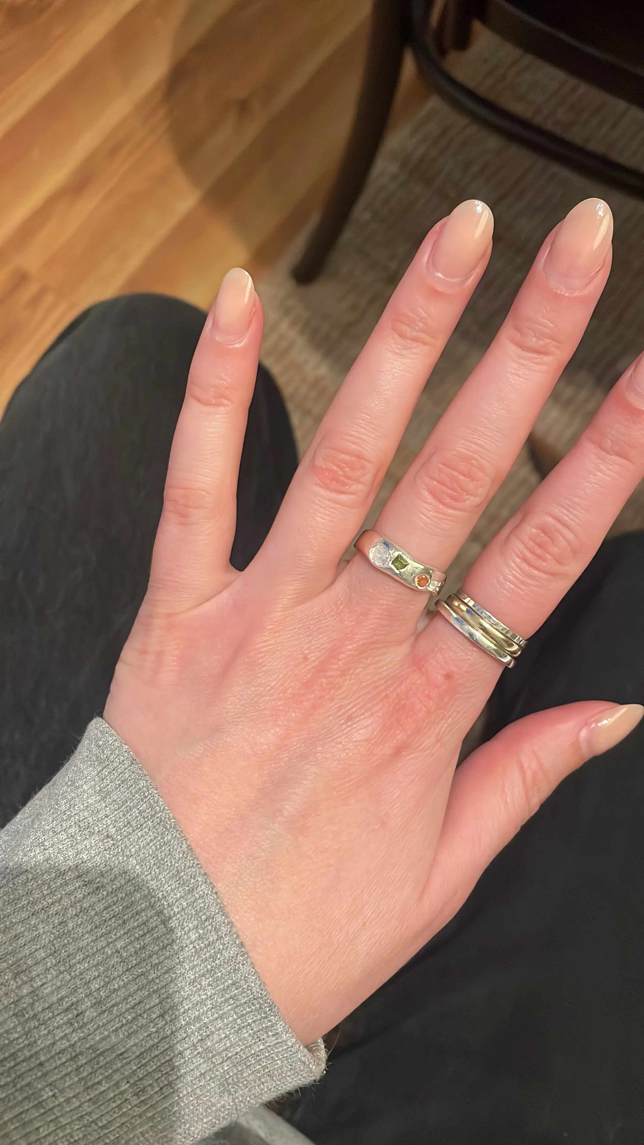Hand mit Ringen auf einem Holzboden.