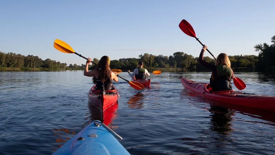 Three people kayaking on a calm lake.