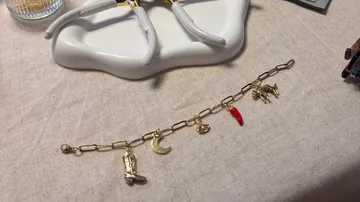 Charm bracelet with pliers on fabric surface.