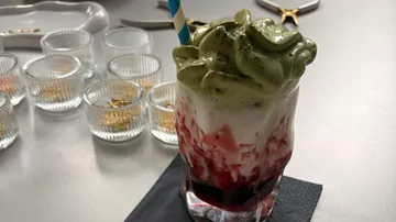 Matcha-bedecktes Getränk mit Beerensauce auf Tisch.