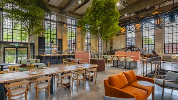 Industrielle Café mit Bäumen und modernen Möbeln.