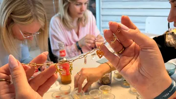 Hands holding charm bracelet; people crafting.
