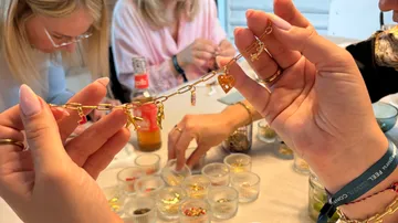 Hands holding charm bracelet, women crafting.