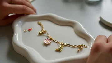 Gold charm bracelet on a ceramic tray.