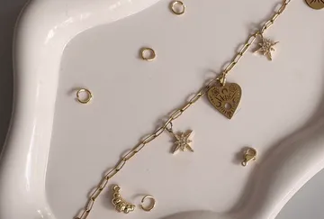Gold charm bracelet with celestial symbols on plate.