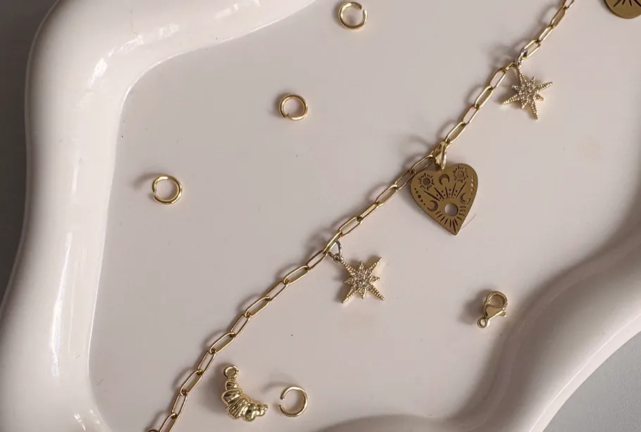 Gold charm bracelet with celestial symbols on plate.