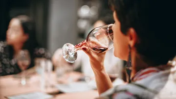 Person drinking wine at social gathering.