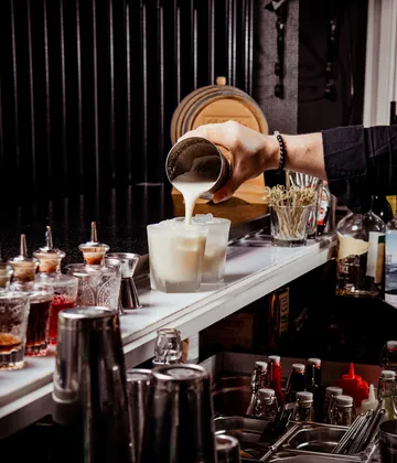Bartender pouring drink into glass at bar.