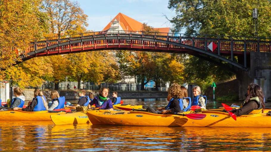 People kayaking on river under a bridge.