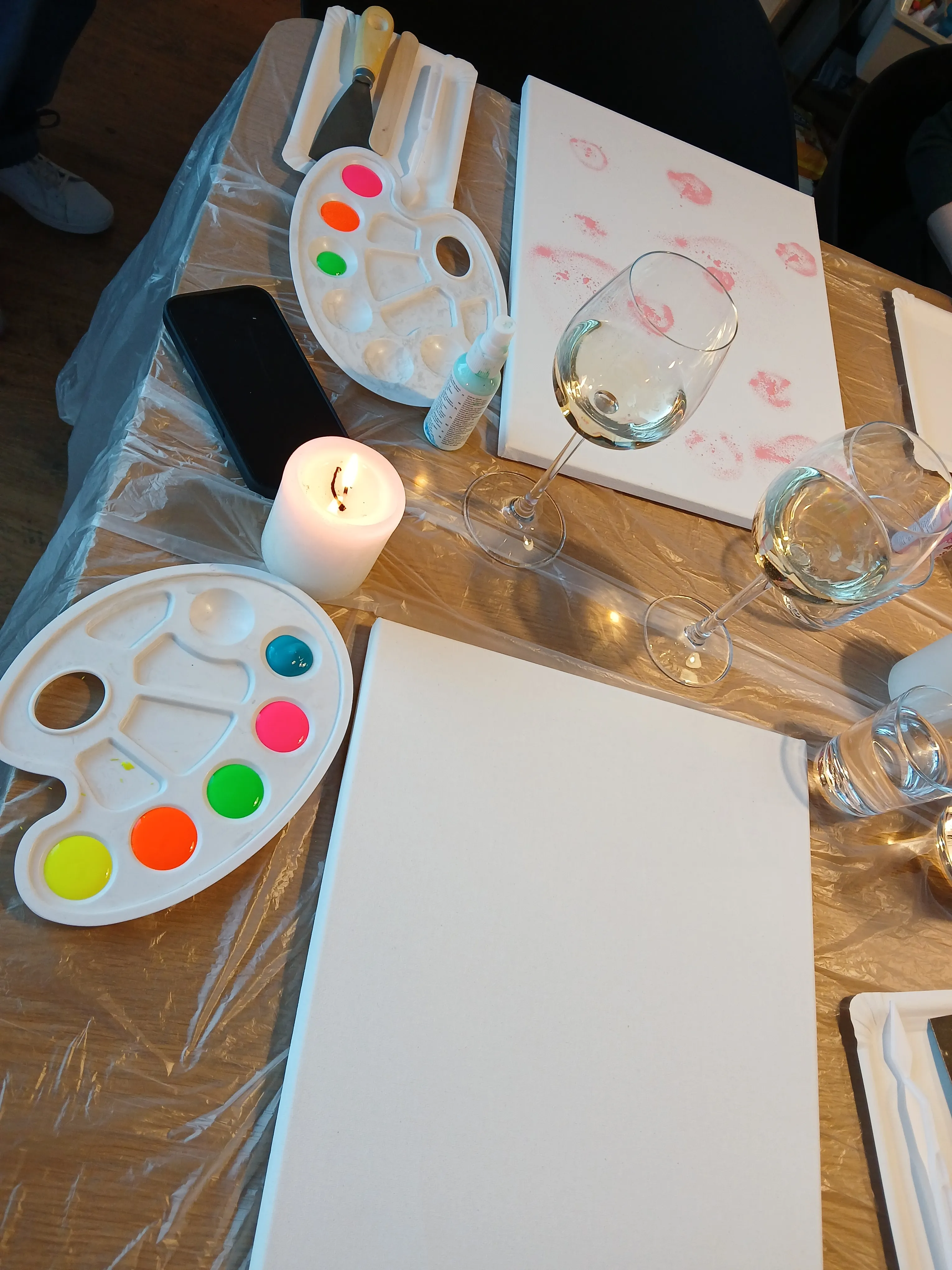Kunstmaterialien und Wein auf einem Tisch.