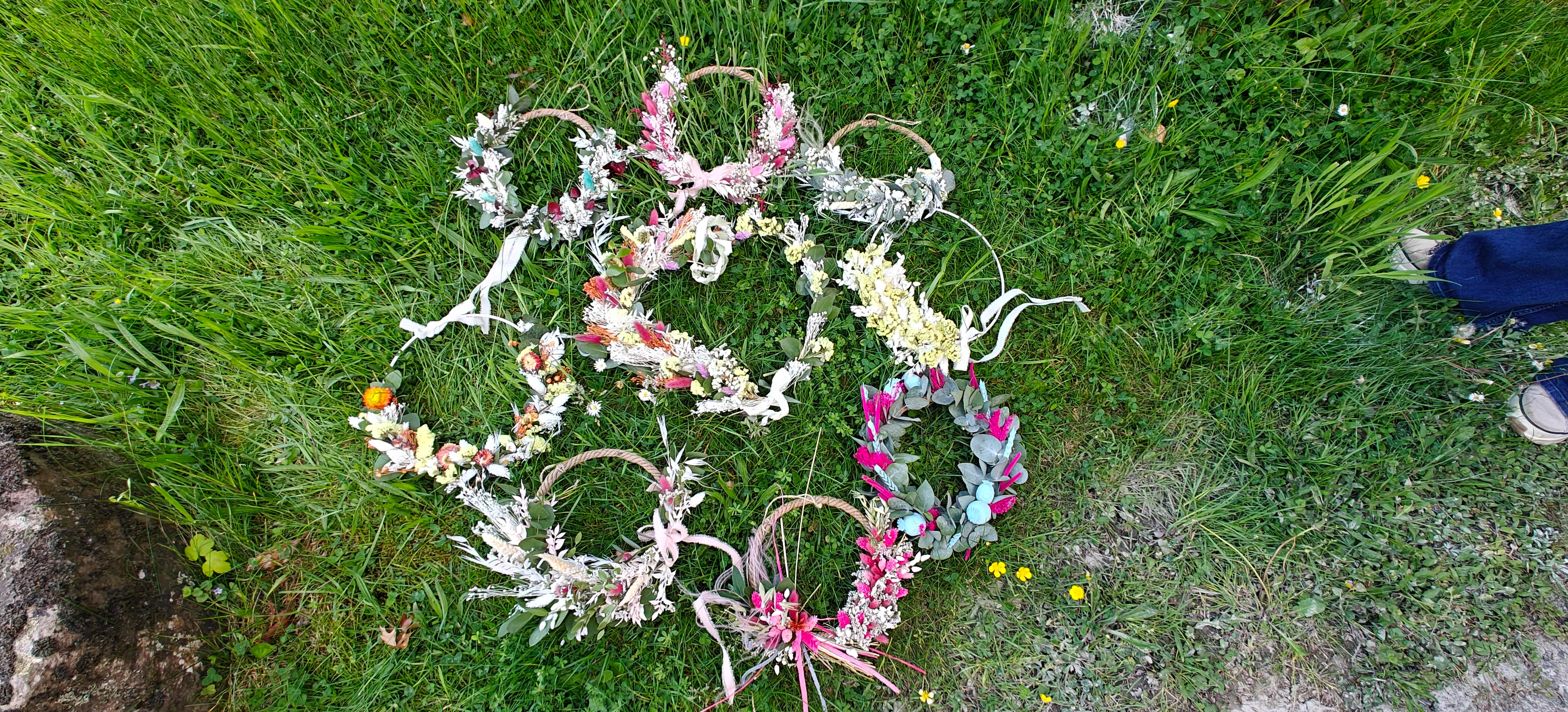 Flower crowns arranged in a circle on grass.