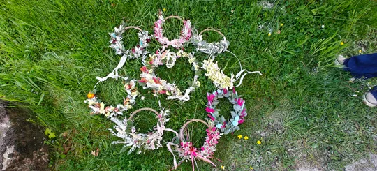 Blumenkränze im Kreis auf Gras angeordnet.
