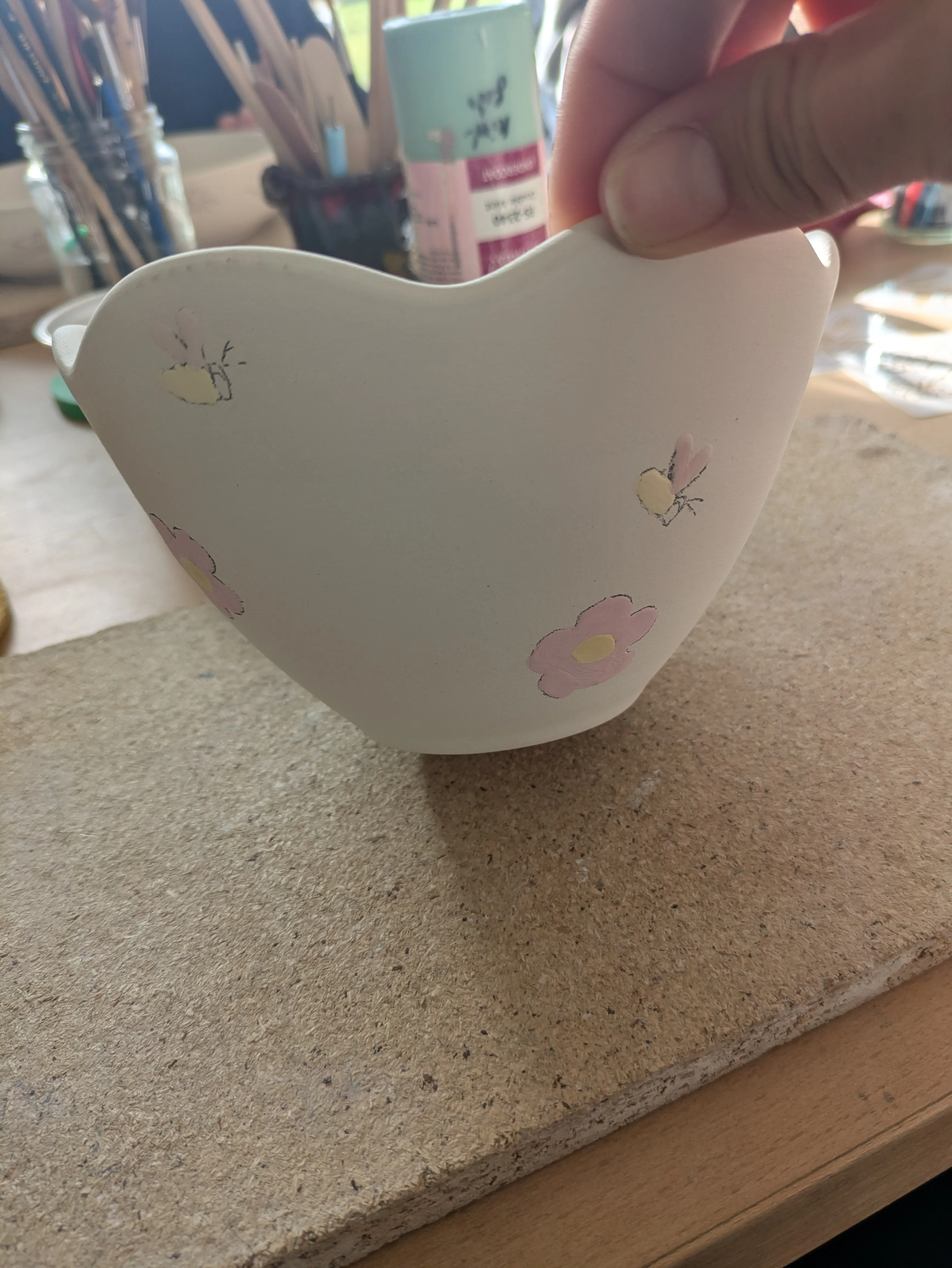 Hand holding painted bowl in art studio.