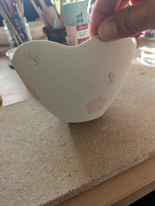 Hand hält bemalte Schale im Kunststudio.