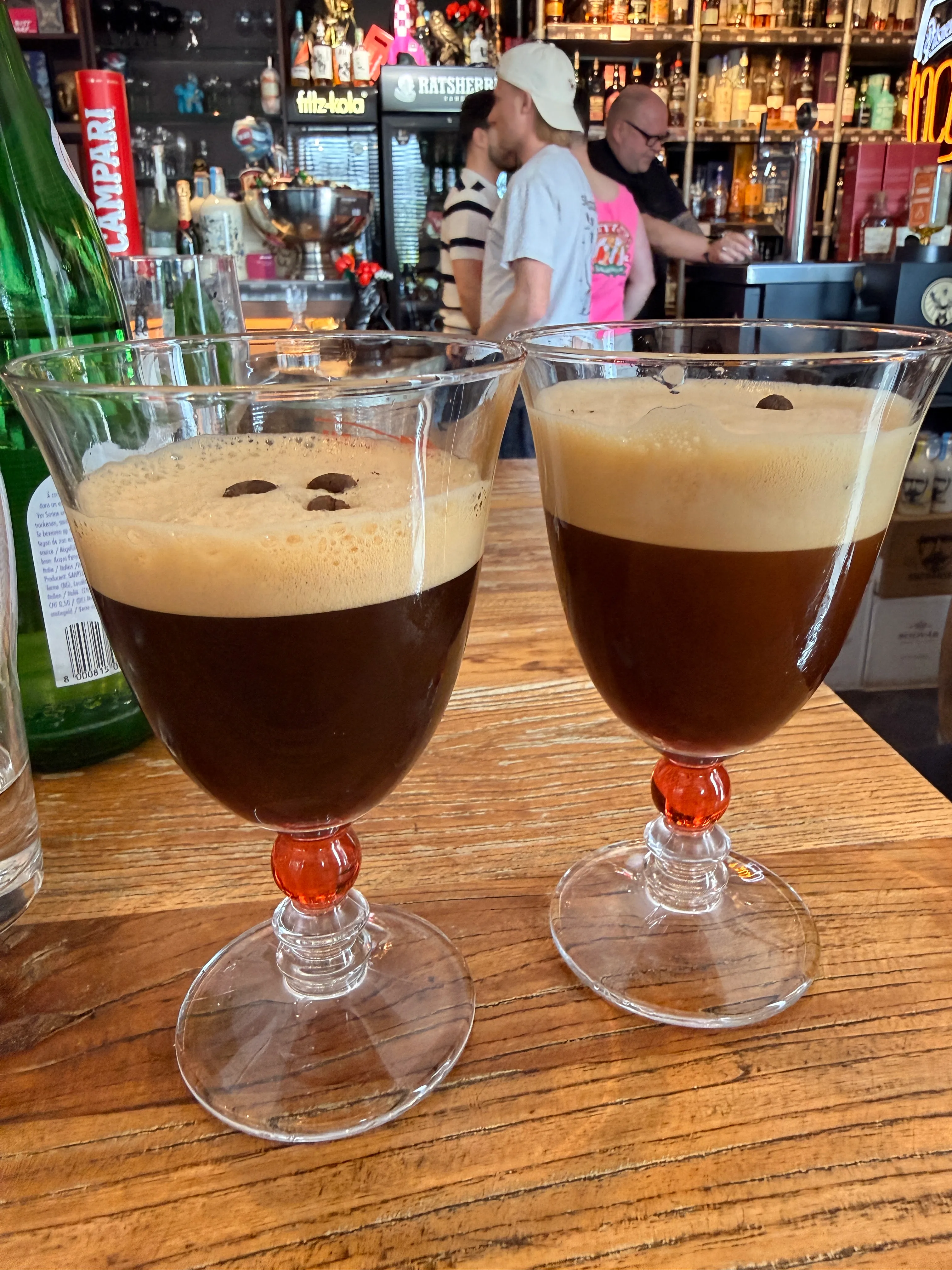 Two espresso martinis on a bar counter.