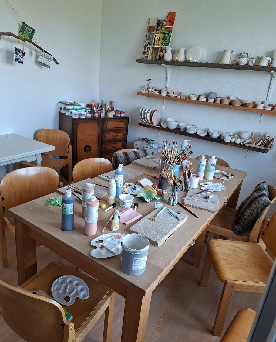 Craft room with table, paints, pottery.