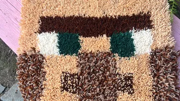 Brown and tan crochet face on wooden surface.