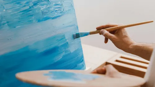 Hand malt blaue Leinwand mit Pinsel drinnen.