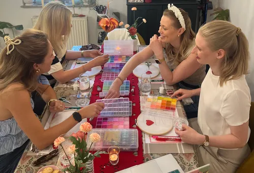 Four women crafting with colorful beads at table.