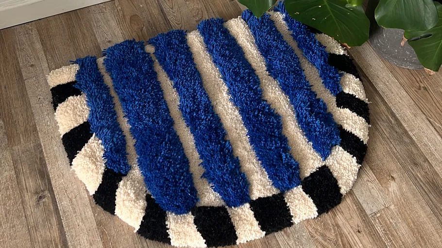 Striped rug on wooden floor beside plant.