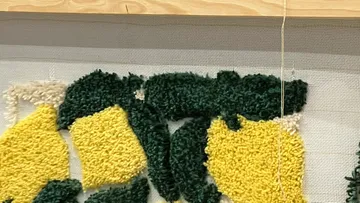 Partially woven tapestry with green and yellow patterns.