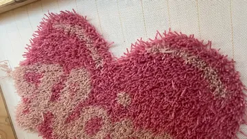 Teilweise fertiger rosa Teppich mit Häkeln.