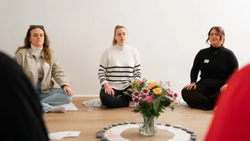 Three women meditating in a peaceful room.