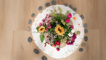 Flowers arranged with stones on a wooden floor.