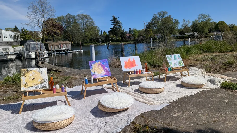 Art easels with paintings by a lakeside.