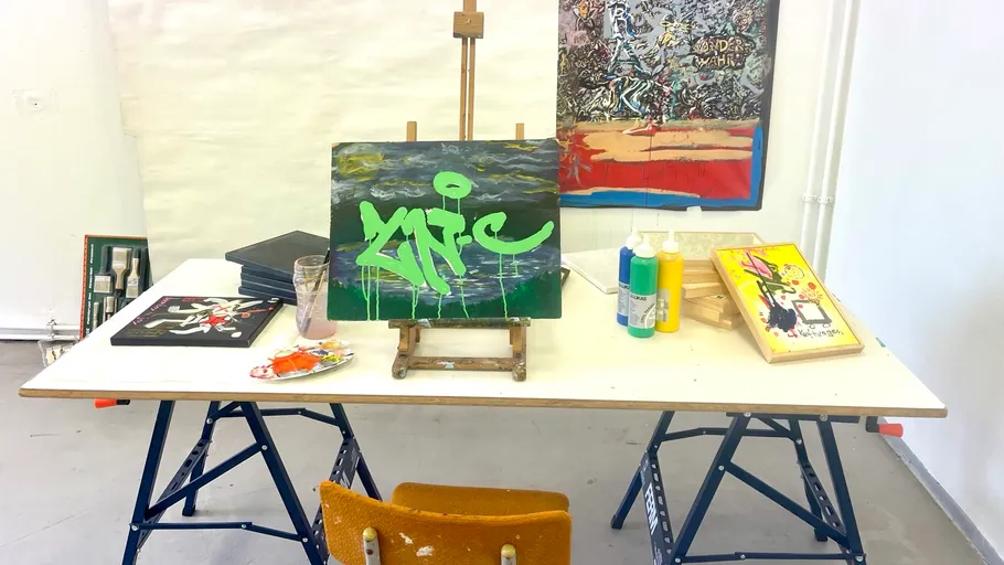 Kunststudio mit Gemälden und Materialien auf Tisch.