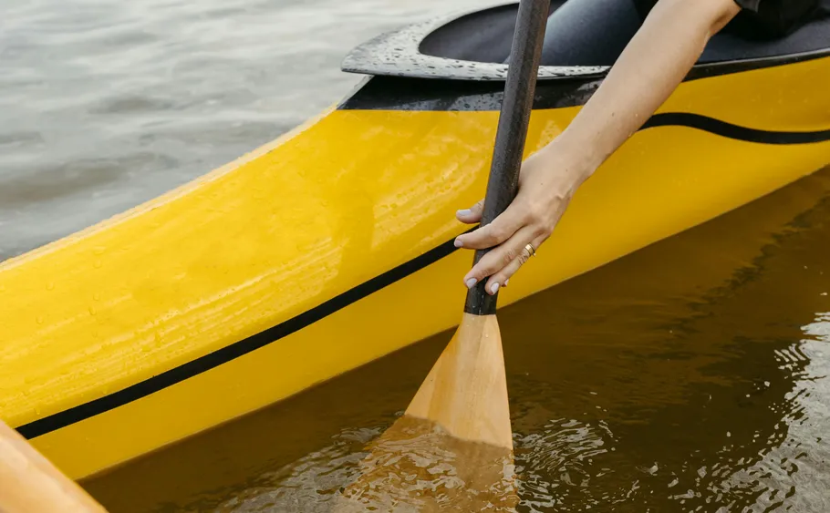 Person paddling yellow kayak on water.