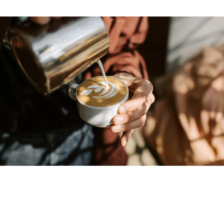 Barista gießt Latte Art in Kaffeetasse.