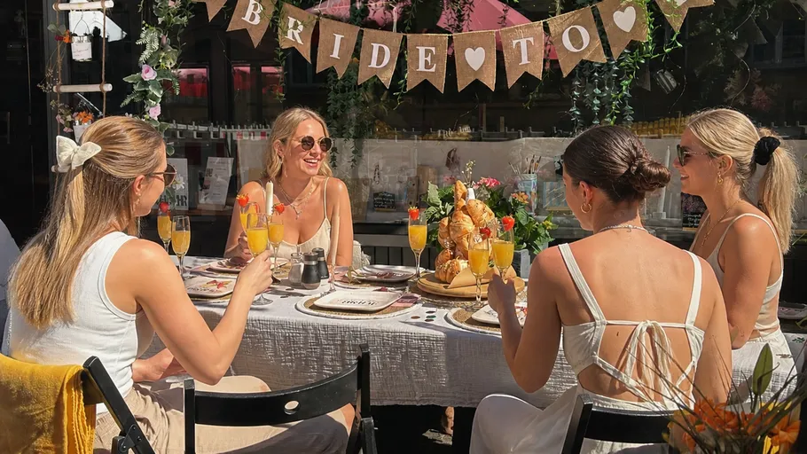 Women celebrating bridal shower outdoors with drinks.