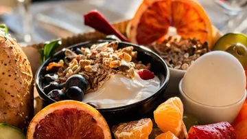 Frühstücksteller mit Joghurt, Obst und Brot.