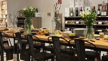 Tisch mit Essen, Wein und Blumen im Geschäft.