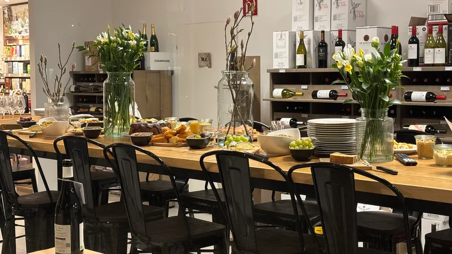 Tisch mit Essen, Wein und Blumen im Geschäft.
