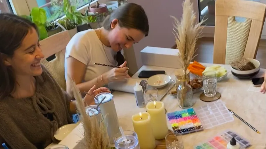 Two women happily crafting together indoors.
