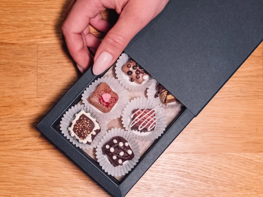 Hand opening box of assorted chocolates.