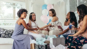 Frauen feiern im Wohnzimmer mit Luftballons.