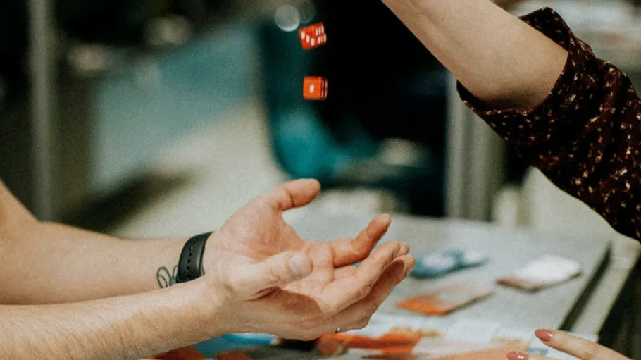 Dice being rolled into waiting hands, indoors.