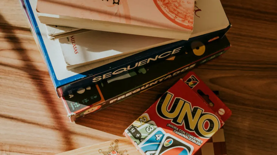 Stack of board games and books on table.